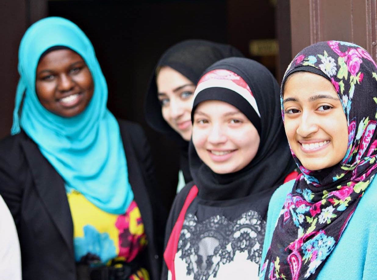 Four young, Muslim women smiling at the camera