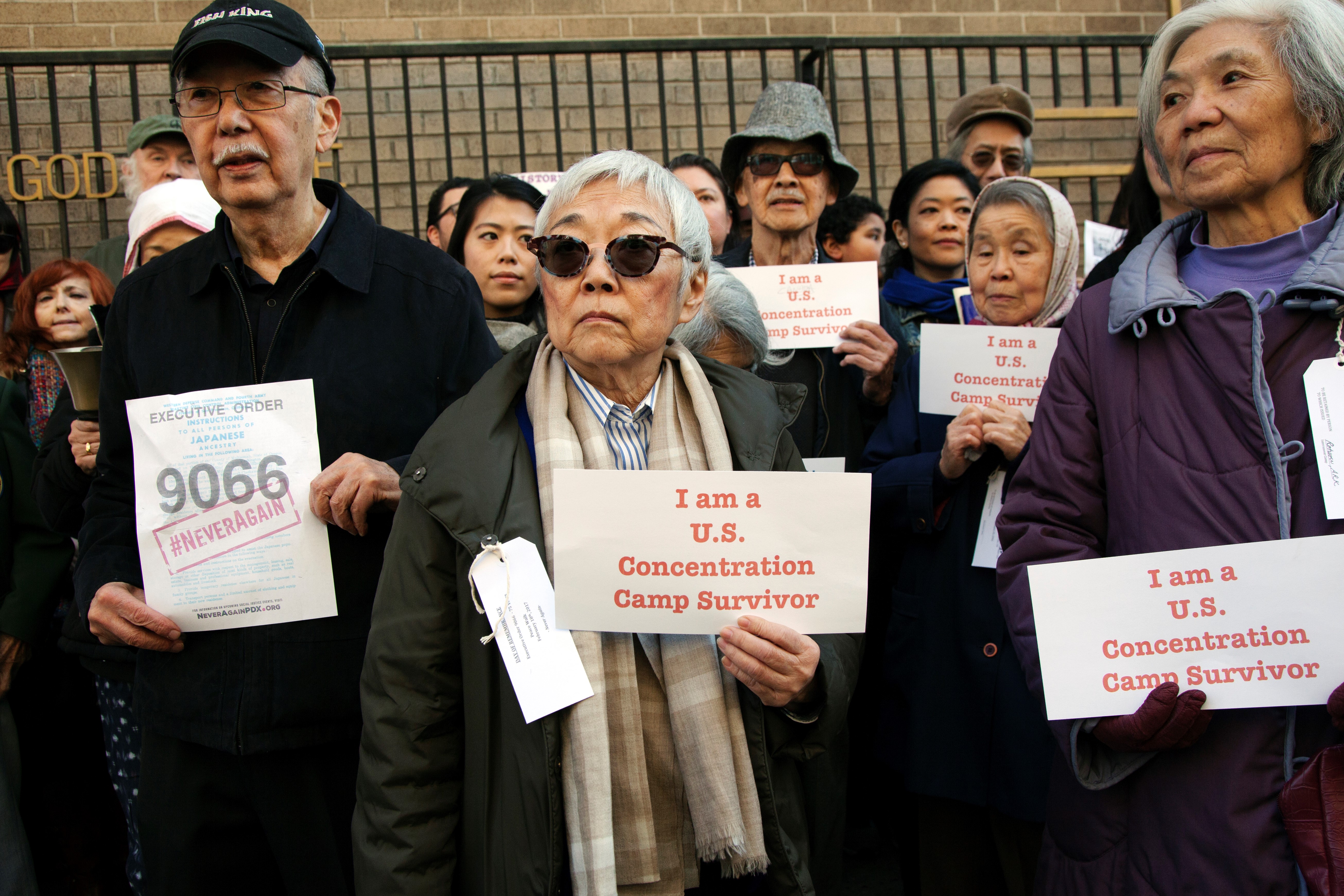 A group of survivors of Japanese internment camps hold signs reading "I am a U.S. Concentration Camp Survivor"