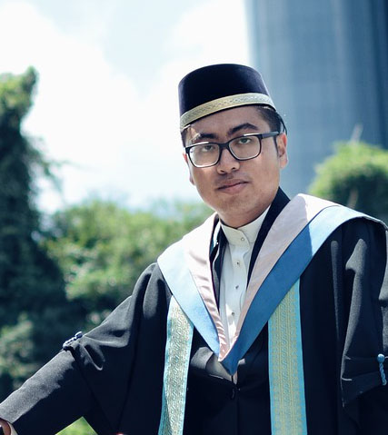 A man in graduation robes and glasses