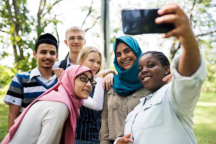 A diverse group of kids gathers around to take a selfie