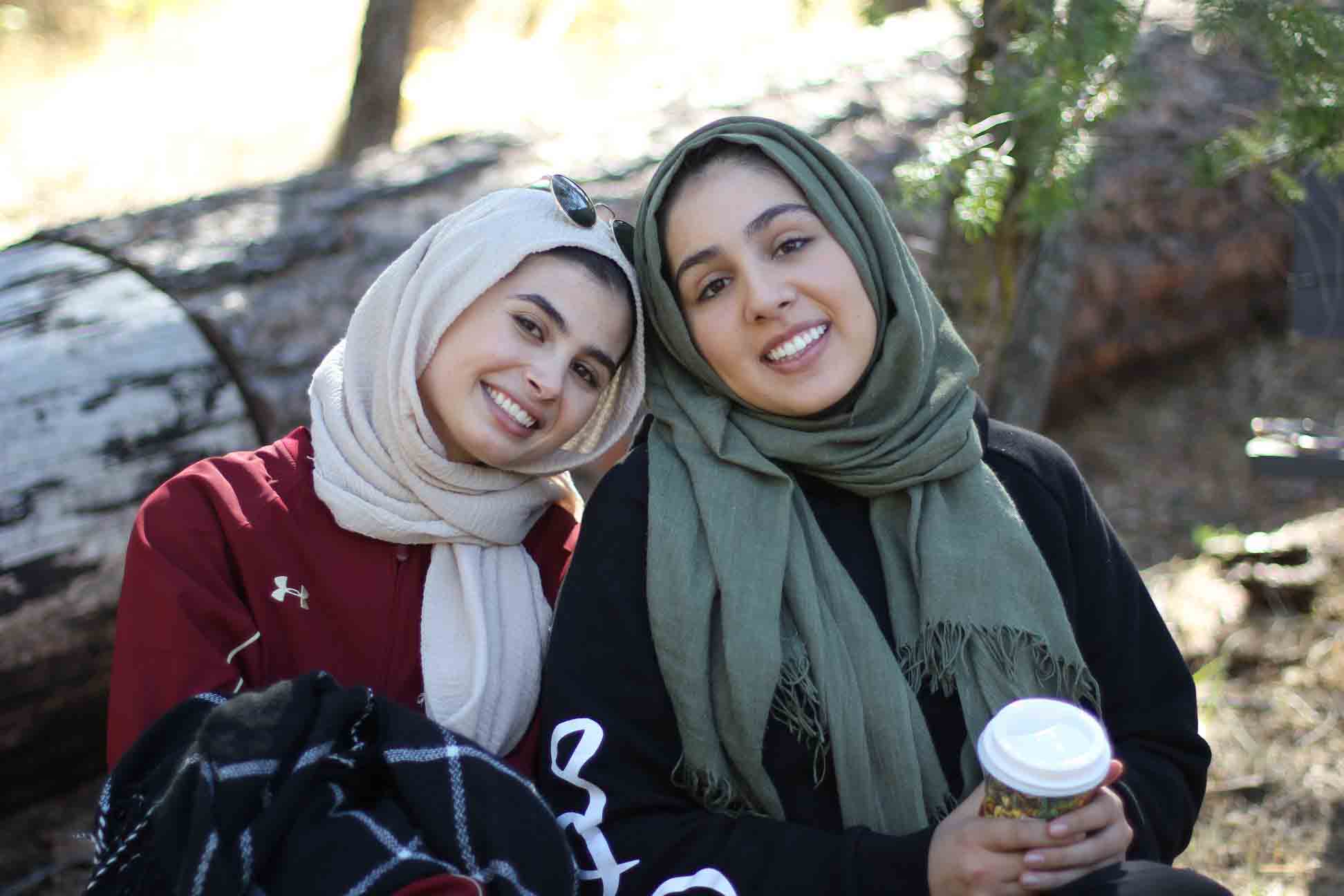 Two college-aged women wearing hijab smiling