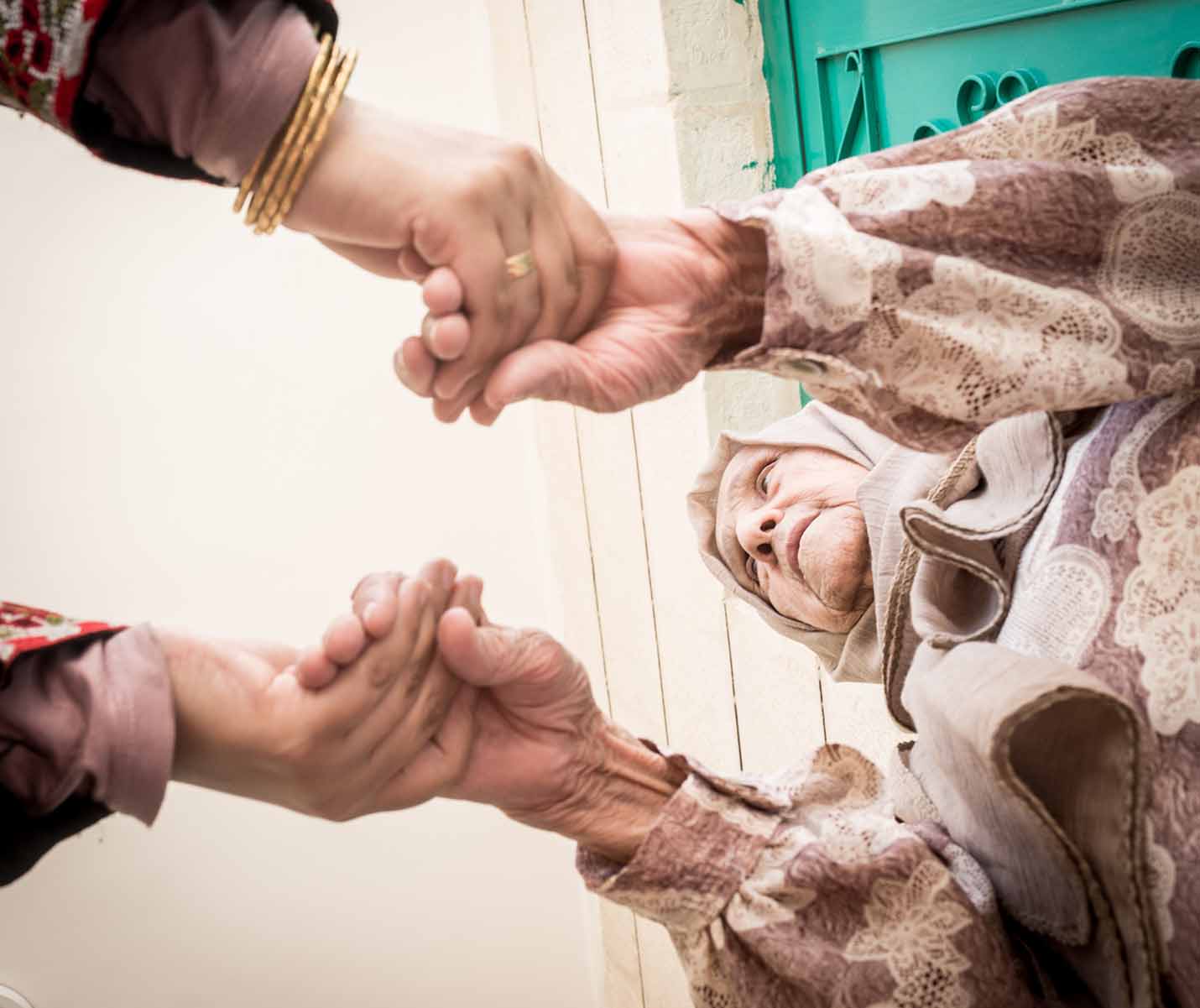 Muslim woman holding senior grandmother hands