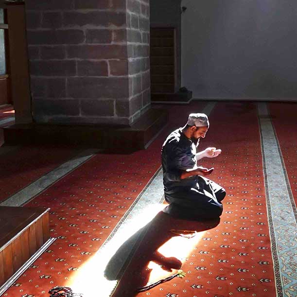 A Muslim man kneels in prayer alone at a mosque