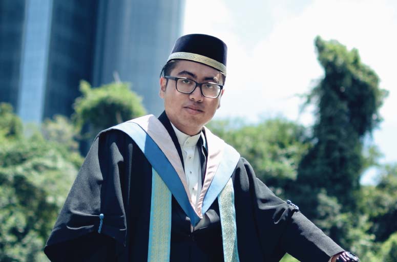 A man in graduation robes and glasses