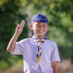 A cub scout raises his hand to say the pledge