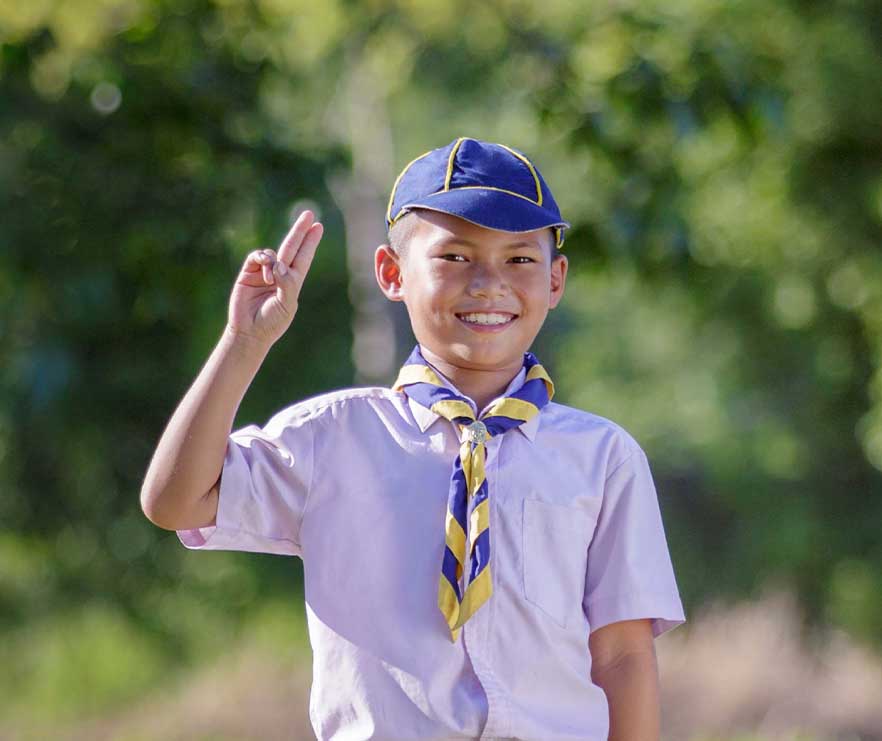 A cub scout raises his hand to say the pledge