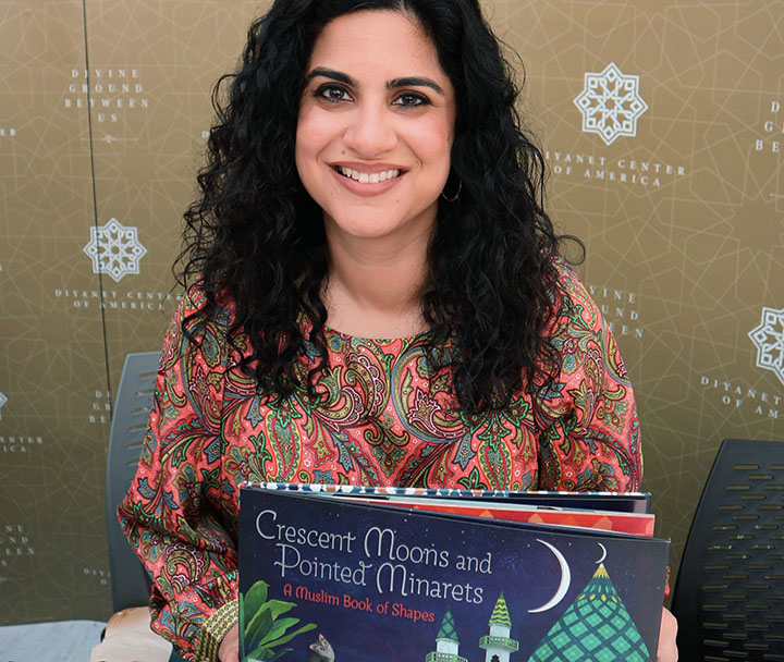 Author Hena Khan holding her children's book, "Crescent Moons and Pointed Minarets"